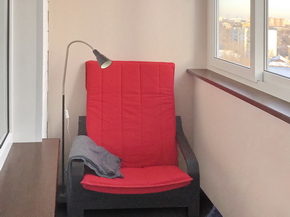Красное кресло на балконе с раздвижным остеклением